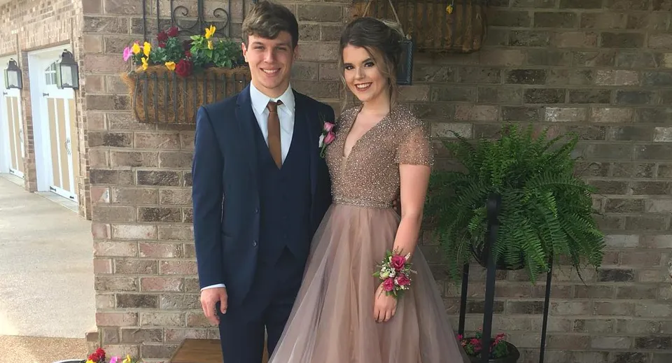 Due giovani della Bishop Rosecrans High School in abiti eleganti in posa davanti a una parete di mattoni.