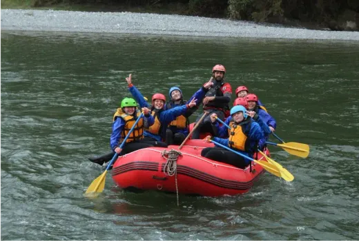 Eine Gruppe Jugendlicher fährt im Schlauchboot einen Fluss in Neuseeland hinunter