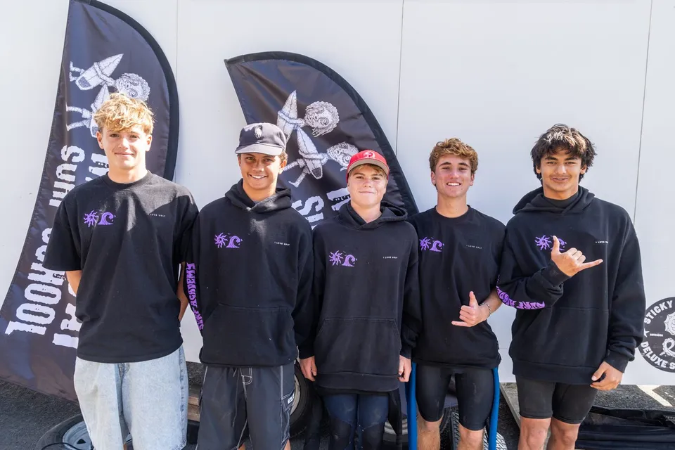 Un gruppo di studenti della Whangamata Area School indossa felpe nere davanti a uno schermo con un teschio.