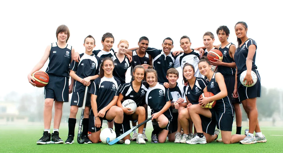 Un gruppo di giovani atlete si trova su un campo d'erba e posa insieme nel campus dell'Avondale College.