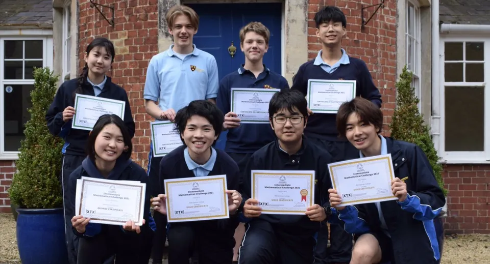 Studenti del Bishopstrow College sono davanti a un edificio in mattoni e mostrano certificati e premi.