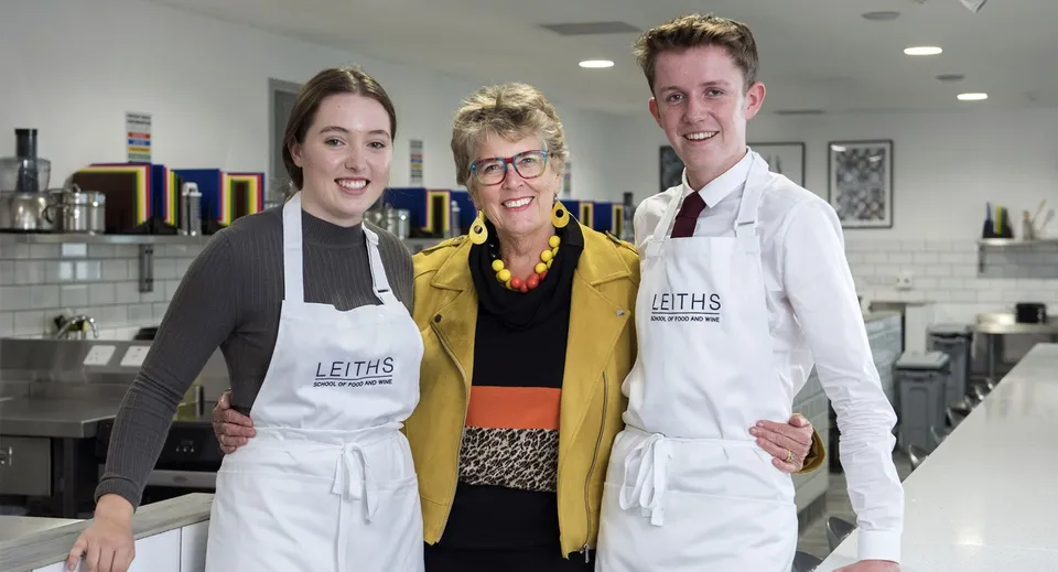 Tre persone indossano grembiuli con il logo Leith's nella cucina della Truro School.