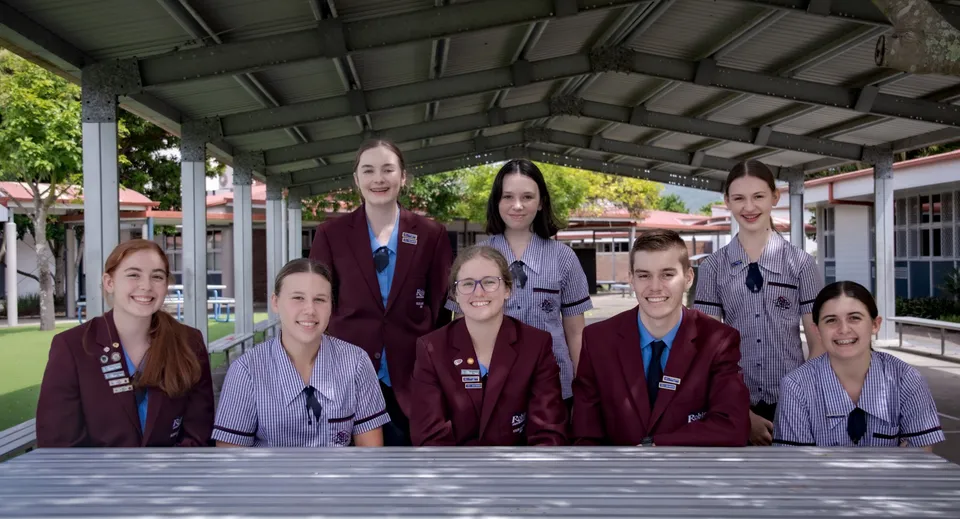 Un gruppo di studentesse della Robina State High School in divise rosse abbinate si trova sotto una struttura esterna coperta.