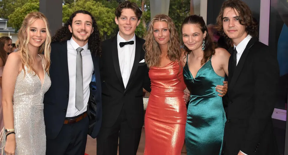 Un gruppo di studenti ben vestiti posa su un tappeto rosso durante un evento al Kawana Waters State College.