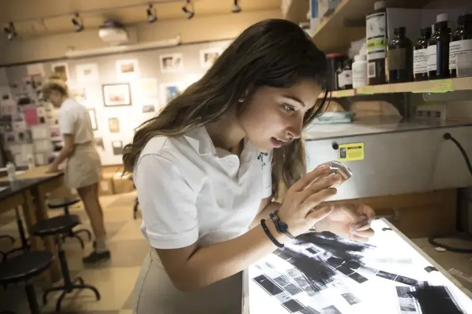 Una studentessa della Woodward Academy è in piedi con un tablet in un caffè e si concentra sul dispositivo.
