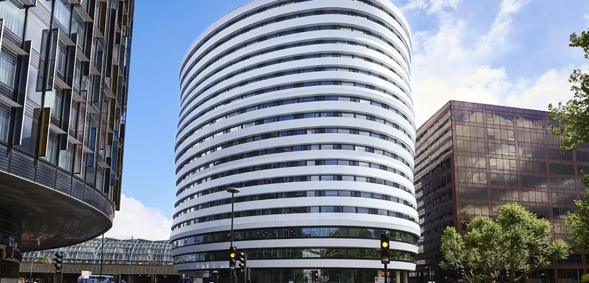 Il moderno grattacielo del DLD College London a più piani e grandi finestre sotto un cielo sereno.