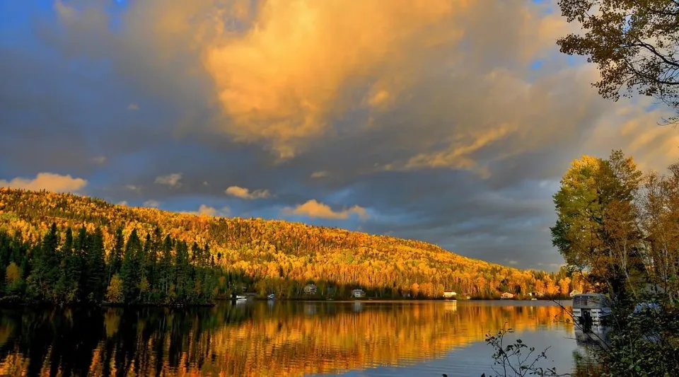 Un lago tranquillo con i colori dell'autunno sotto un cielo nuvoloso vicino alla Our Lady of the Rockies High School.