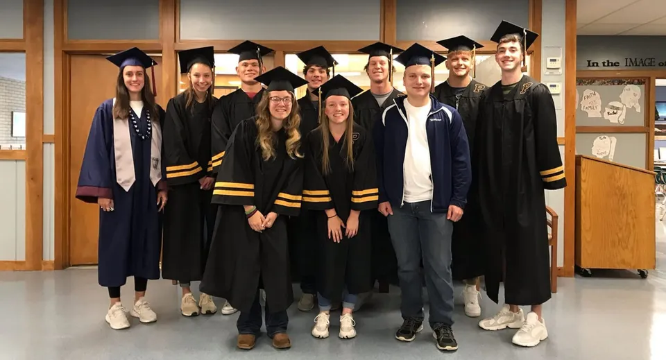 Un gruppo di diplomate e diplomati in abito da diploma sul campus della Lester B. Pearson Catholic High School.