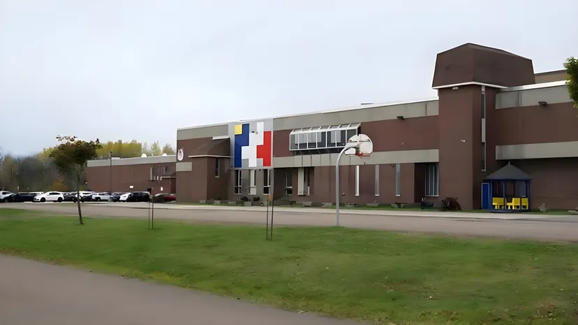 L'edificio moderno a più piani della École Mathieu-Martin sorge su un prato con un canestro da basket in primo piano.