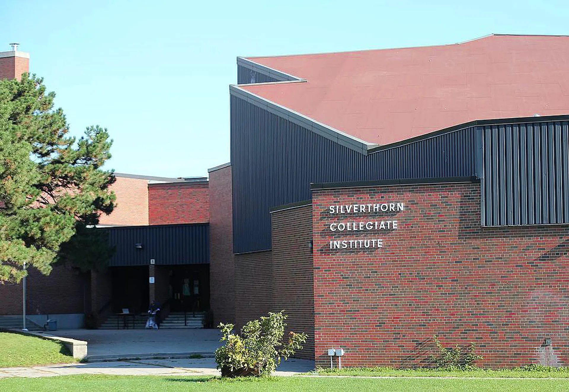 L'edificio moderno del Silverthorn Collegiate Institute con facciata in mattoni e metallo è circondato da alberi.