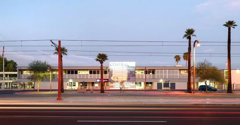 Un edificio commerciale con palme in primo piano sotto un cielo terso vicino al Phoenix Union High School District.
