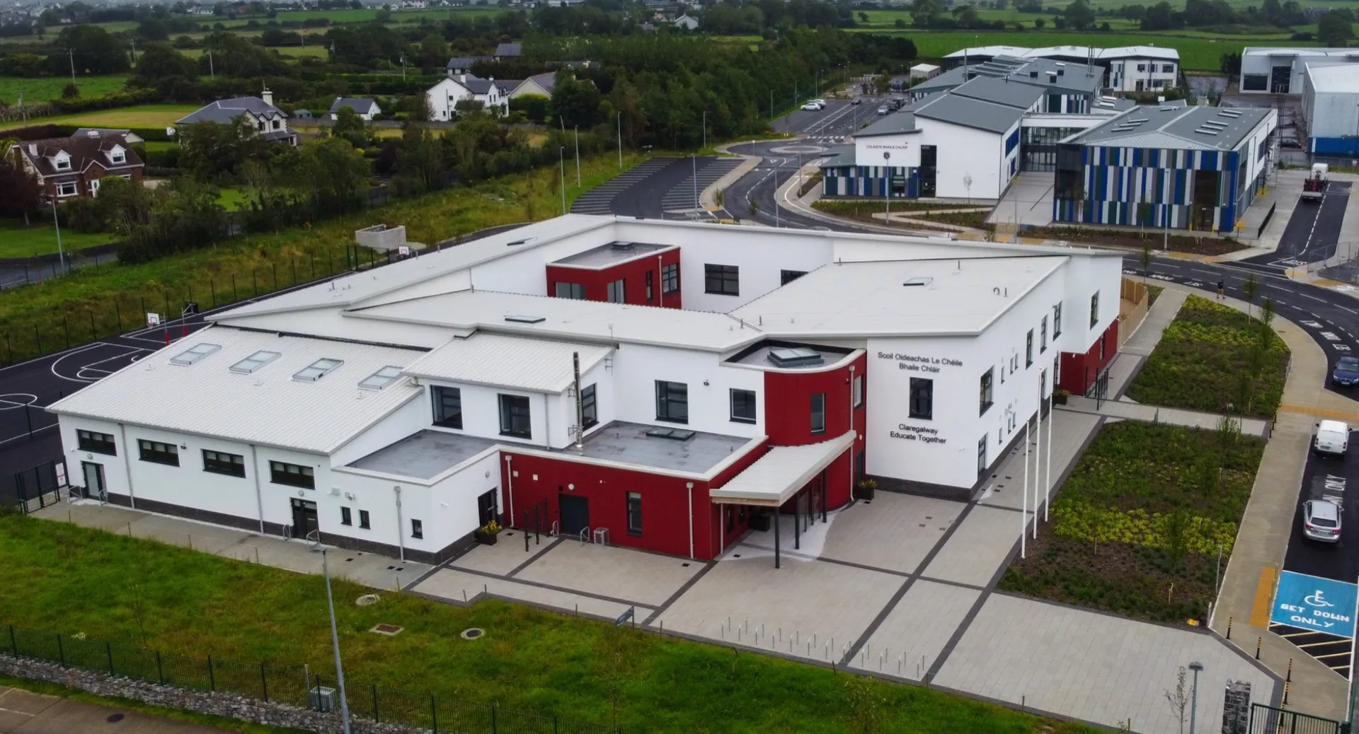 L'edificio moderno a più piani della Coláiste Chríost Rí si trova circondato da un'area verde e da altri edifici sullo sfondo.