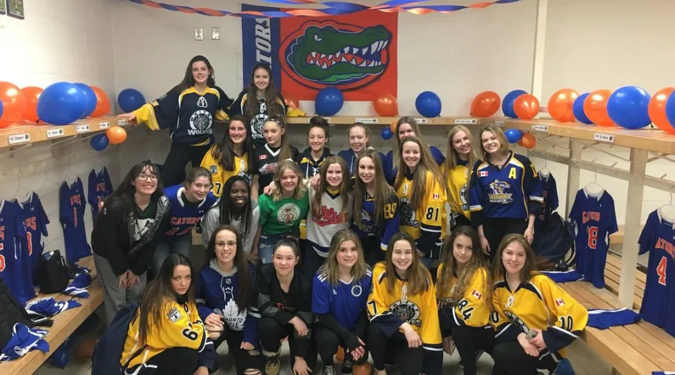 Un gruppo di studentesse della Donald A. Wilson School posa in divisa sportiva davanti al logo Gator in una stanza decorata.