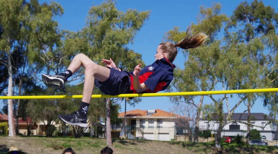 Un giovane atleta esegue un salto in alto sul campo sportivo della Morley Senior High School.