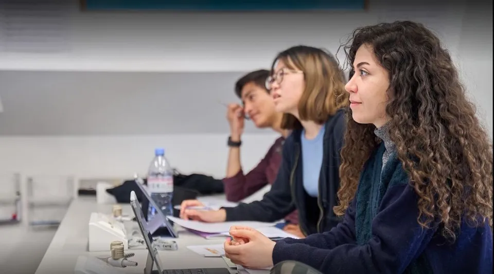 Studenti della Guildhouse School London siedono a un tavolo e lavorano insieme in classe.