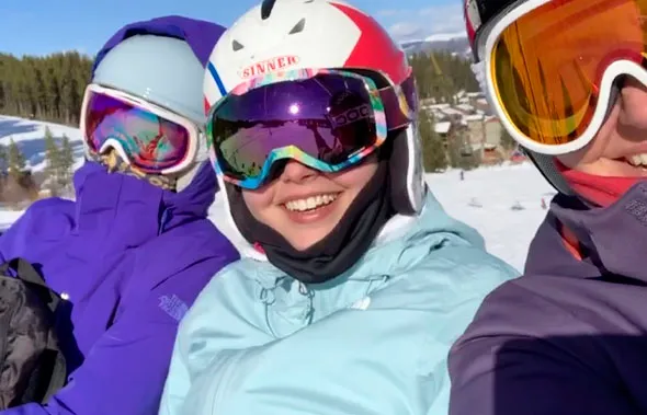 Tres personas con cascos y gafas de esquí posan sonrientes en la nieve