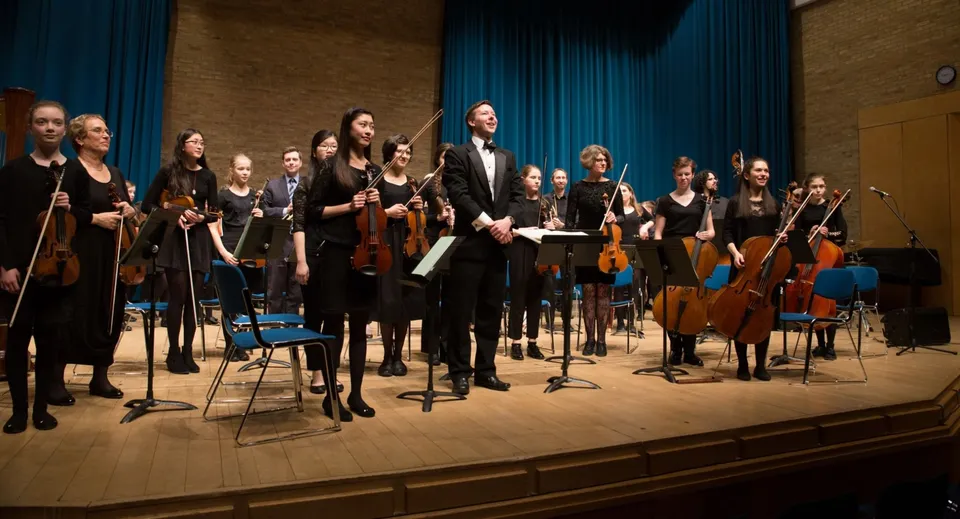 L'orchestra della Stephen Perse Foundation esegue un concerto su un palco con tende blu.