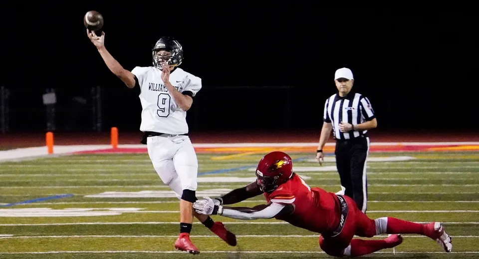 Un giocatore di football americano della JSerra Catholic High School lancia il pallone mentre un avversario tenta di placcarlo.