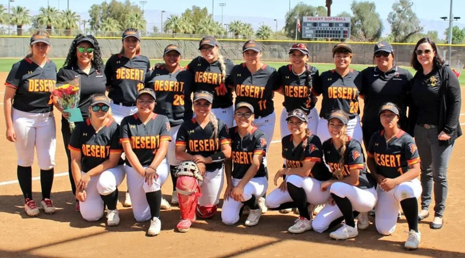 Un gruppo di giovani giocatrici di softball si trova insieme sul campo sportivo del College of the Desert.