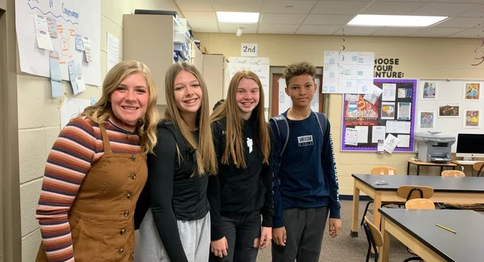 Quattro studentesse sono insieme in un corridoio della Urbandale High School davanti a poster educativi.