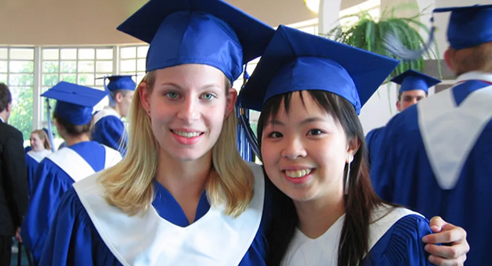 Due studentesse della Langley Fine Arts School sorridono e posano con la toga accademica durante una cerimonia di diploma.