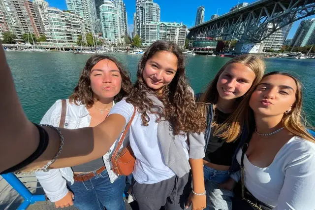 Quattro studentesse si scattano un selfie sul lungomare davanti allo skyline di una città