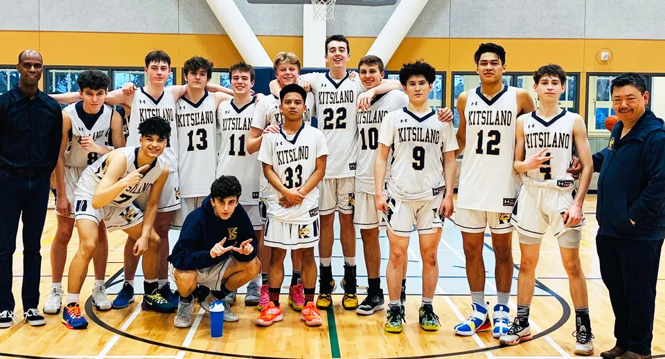 Un gruppo di studenti della Kitsilano Secondary School in posa insieme sul campo da basket con il canestro visibile sullo sfondo.