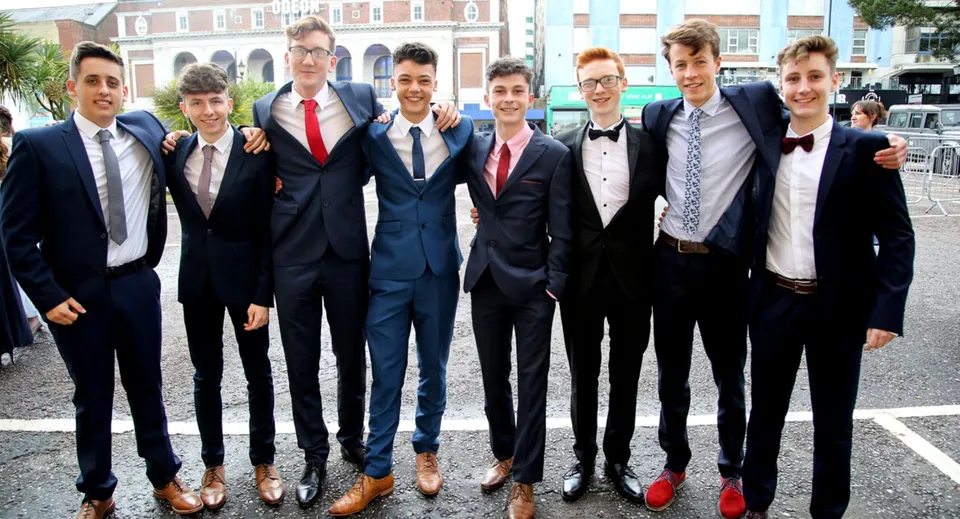 Un gruppo di studenti del Presentation Brothers College in abiti formali davanti a un edificio in mattoni.