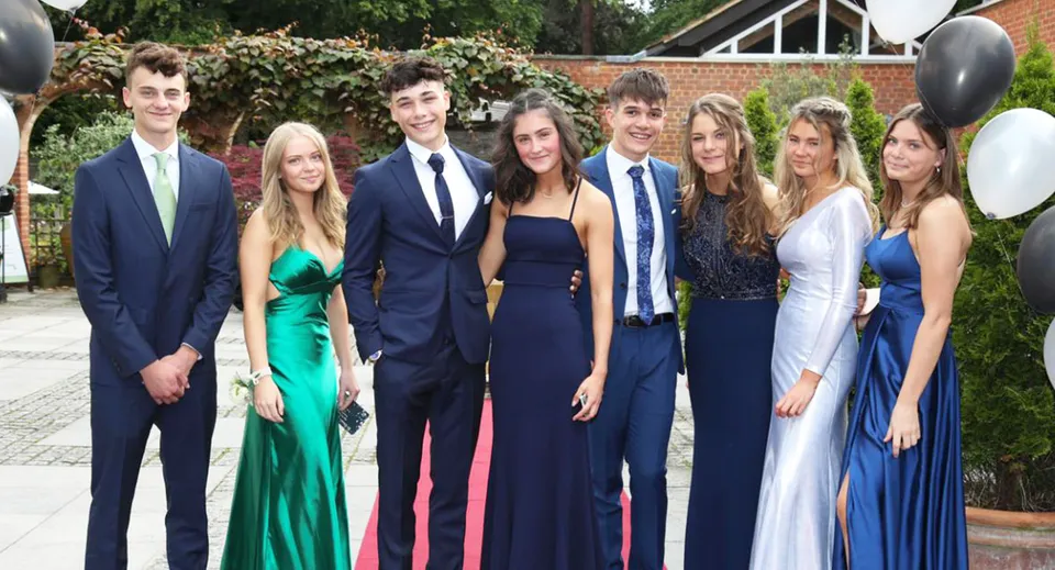Un grupo de estudiantes bien vestidos posan juntos frente a un fondo verde en el campus de la St. Edward's School en Poole.