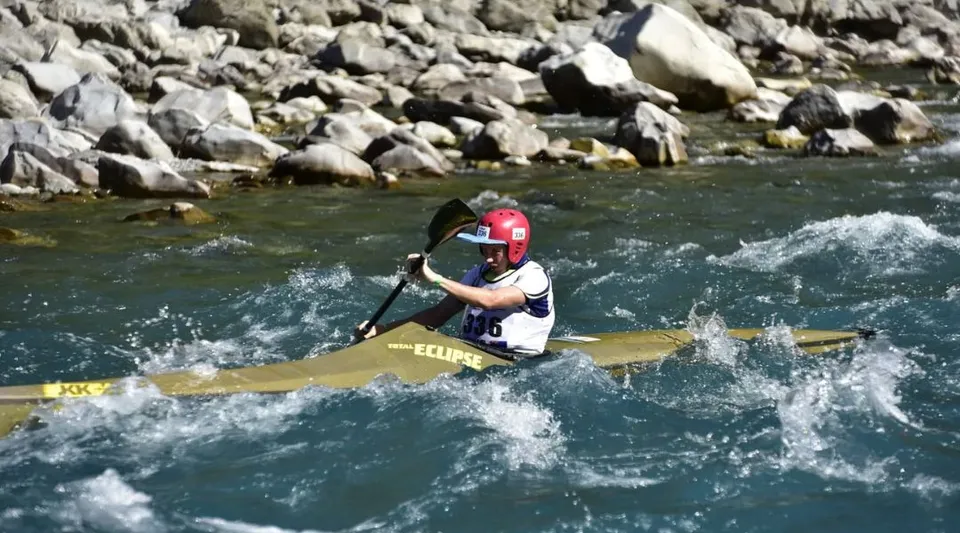 Uno studente della Kaiapoi High School naviga con un kayak giallo tra le rapide di acqua bianca in un ambiente roccioso.