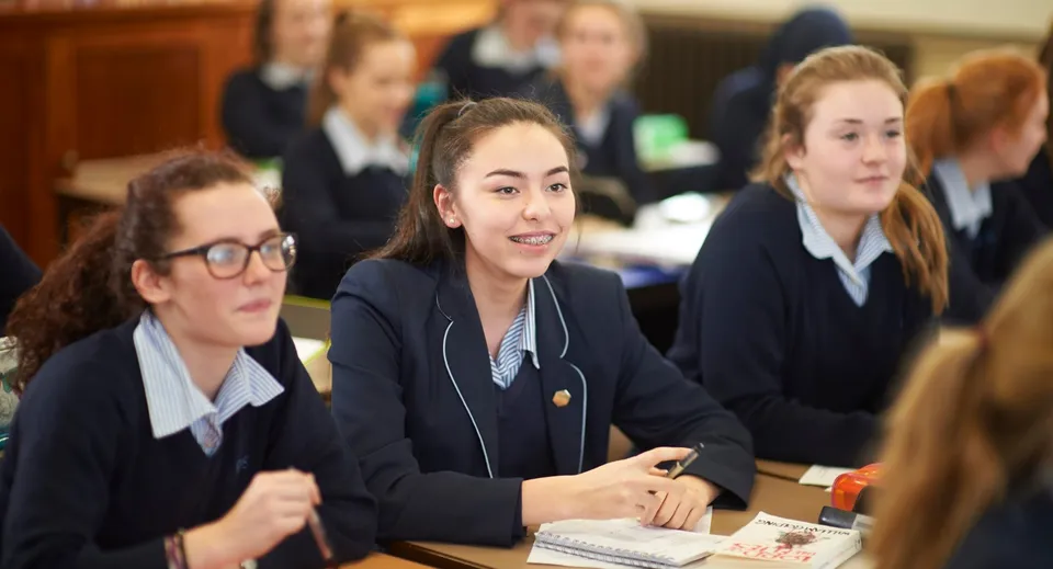 Un gruppo di studentesse della Royal Masonic School for Girls è seduto ai banchi in classe e lavora insieme.