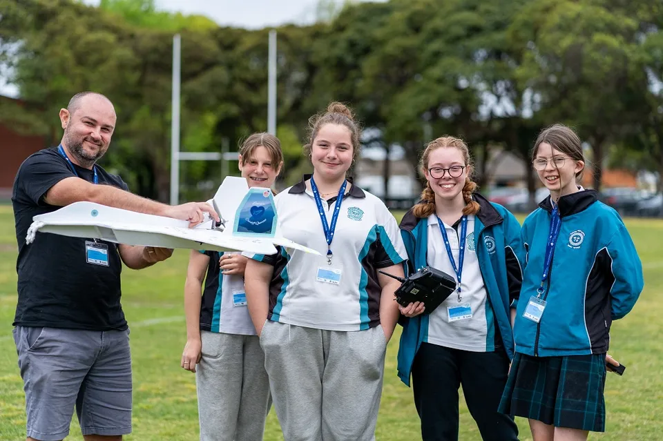 Studenti e insegnanti della Cardiff High School si trovano insieme su un campo sportivo all'aperto.