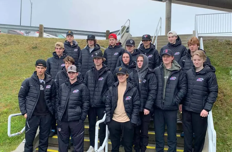 Un gruppo di studenti della O'Donel High School è in piedi davanti a uno stadio con giacche e cappelli neri.