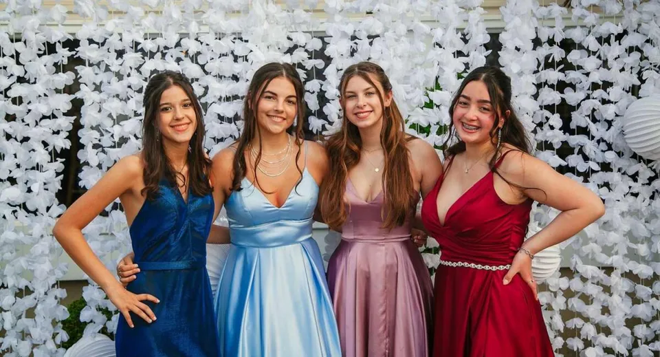 Quattro studentesse della Johnston Heights Secondary School posano insieme davanti a uno sfondo bianco.