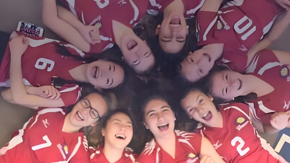 Un gruppo di giovani studentesse in maglia rossa si raduna sul campus della École Arc-en-ciel.