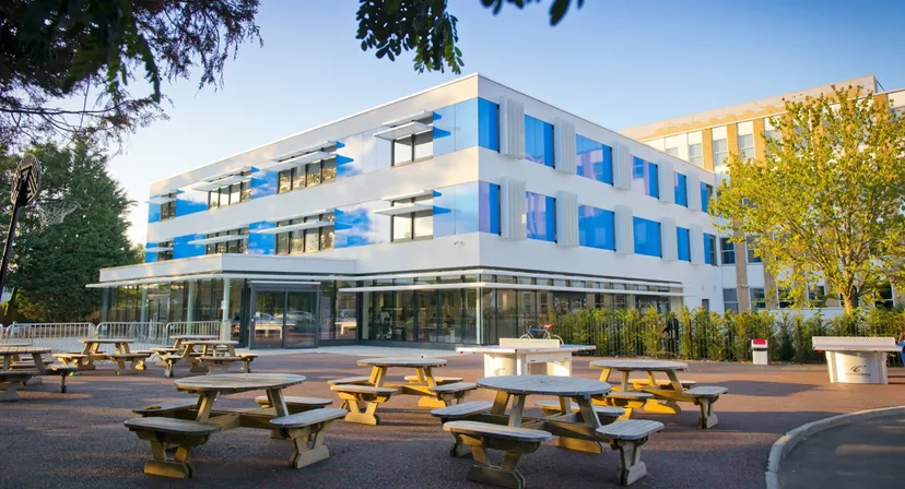 L'edificio moderno della The Worthgate School Canterbury, con facciata bianca e blu e tavoli da picnic nel cortile.