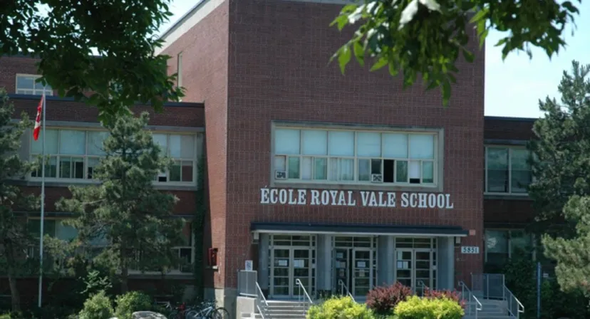 L'edificio in mattoni della Royal Vale High School con una targa è circondato da alberi verdi.