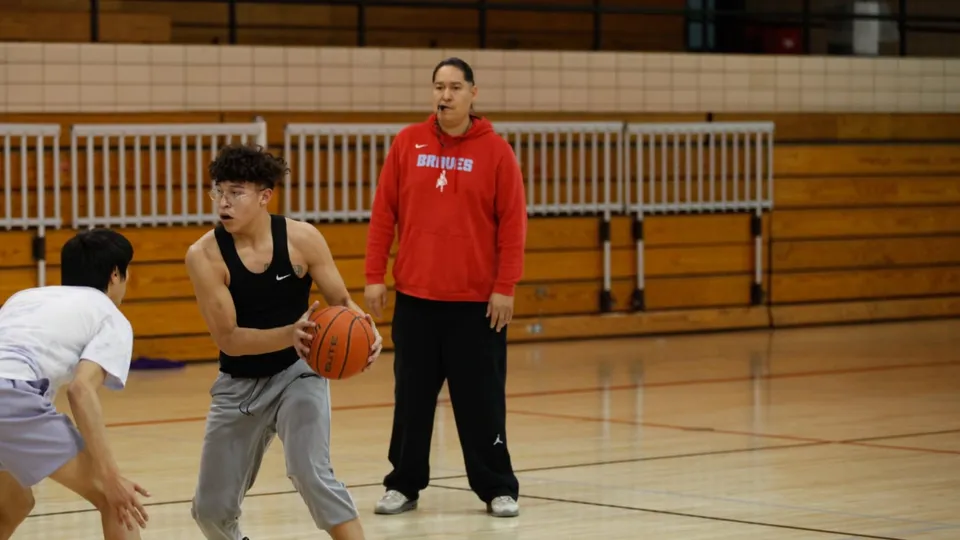 Due studentesse della Eagle Butte High School giocano a pallacanestro in una palestra con pavimento in legno.