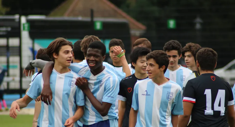 Un gruppo di giovani calciatori si trova sul campo sportivo della TASIS The American International School in England.
