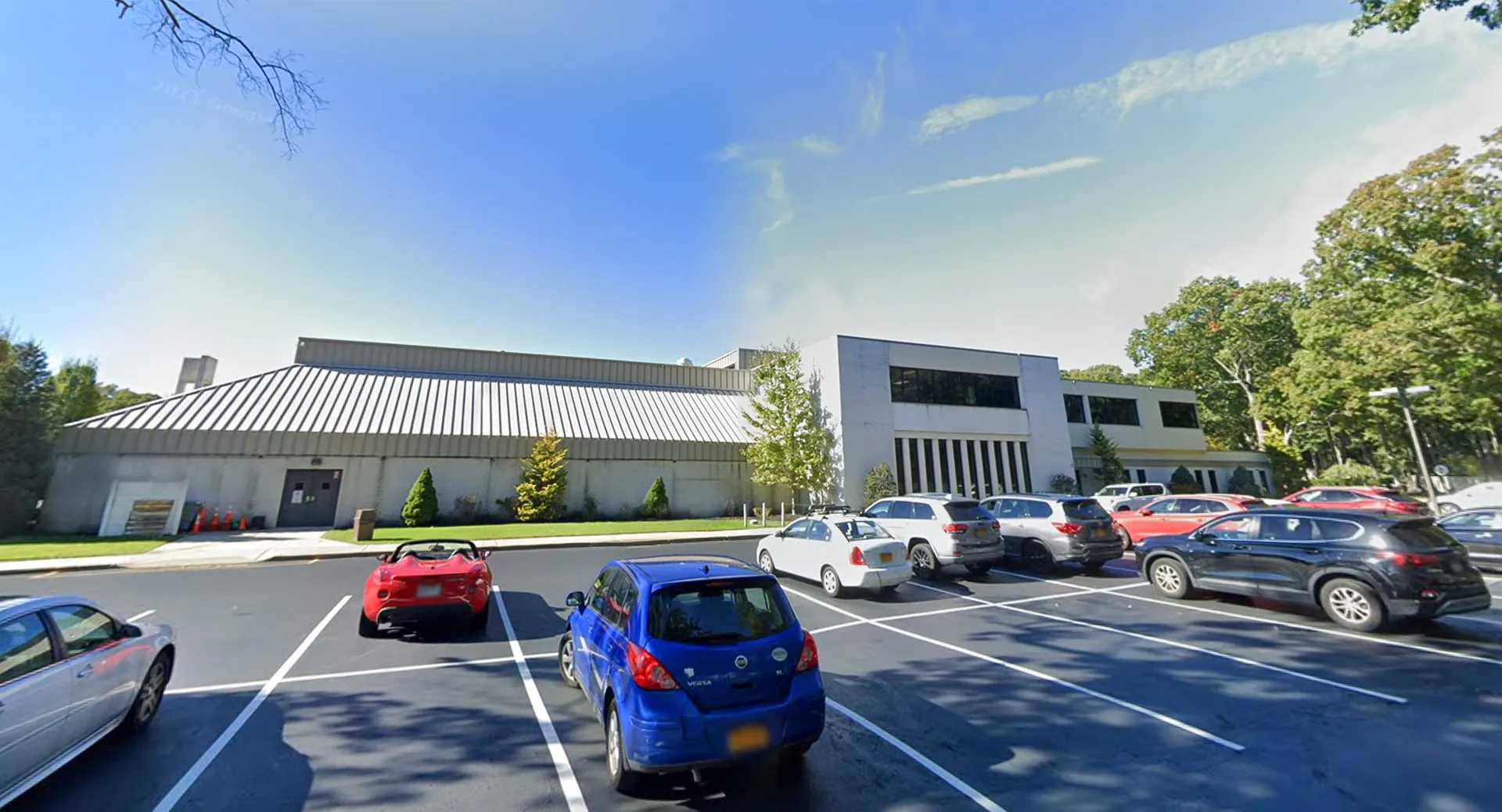 L'edificio scolastico moderno della Smithtown Christian School con parcheggio e alberi in primo piano sotto un cielo blu.