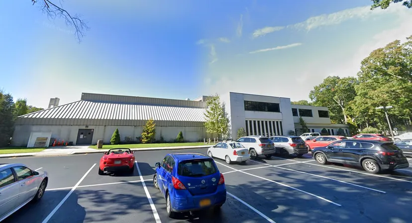 L'edificio scolastico moderno della Smithtown Christian School con parcheggio e alberi in primo piano sotto un cielo blu.
