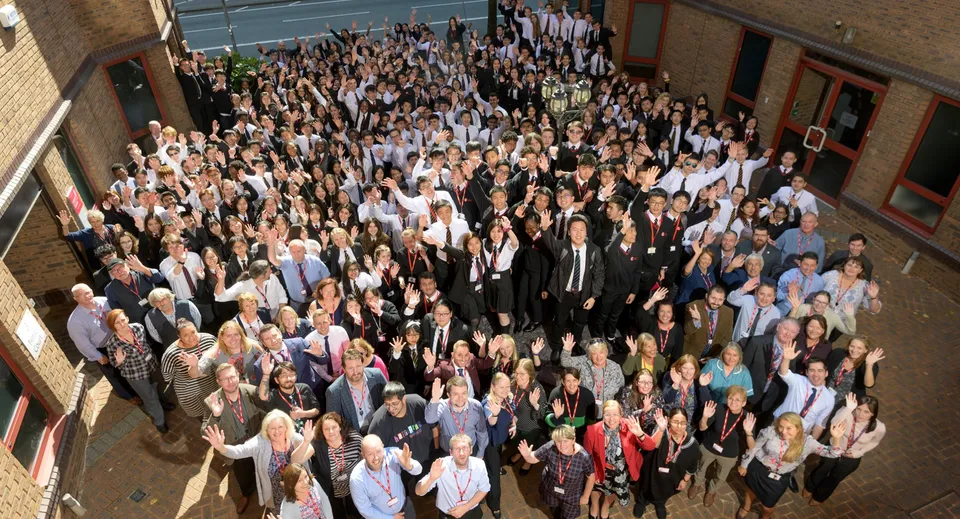 Un grande gruppo di studenti si riunisce nel corridoio del Cardiff Sixth Form College durante un evento formale.