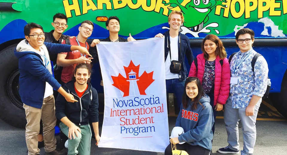 Studenti del Nova Scotia French Program con uno striscione davanti al colorato murale Harbour Hopper.