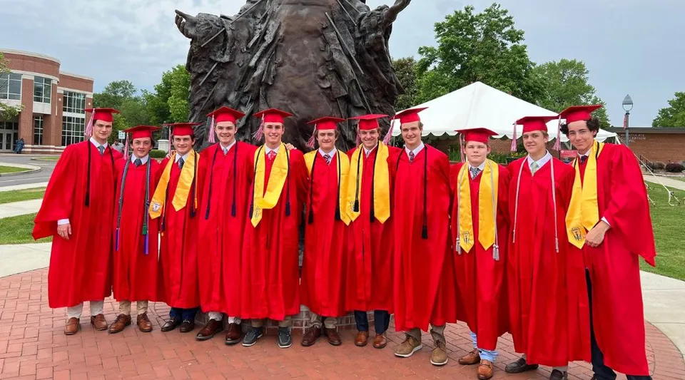 I diplomati della Chaminade College Preparatory School si trovano davanti a una grande statua di bronzo nel campus.