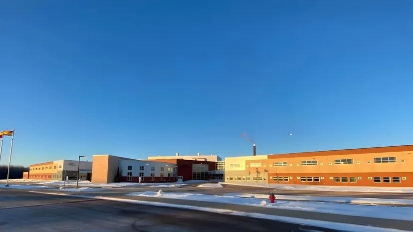 Il moderno edificio scolastico della École L’Odyssée è circondato da un paesaggio innevato sotto un cielo azzurro e limpido.