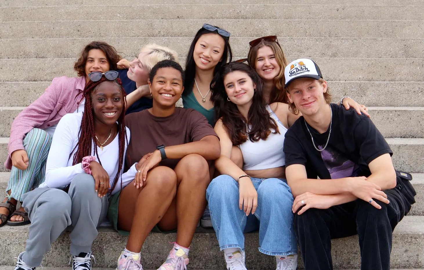 Grupo de jóvenes sonrientes sentados juntos en una escalinata al aire libre
