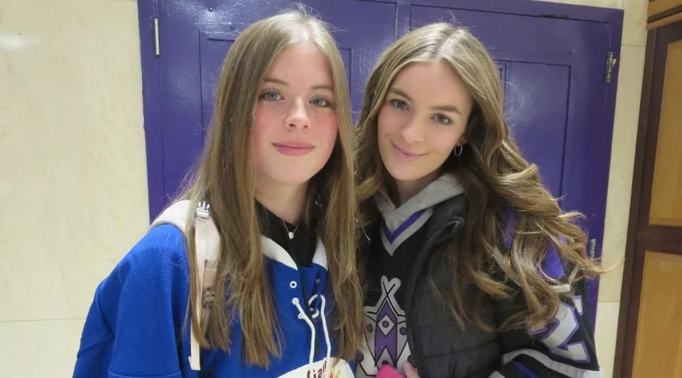 Due studentesse della Thousand Islands Secondary School sono in piedi davanti a una porta lilla e sorridono alla telecamera.