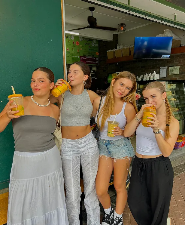 Cuatro chicas con batidos posando delante de un quiosco de zumos