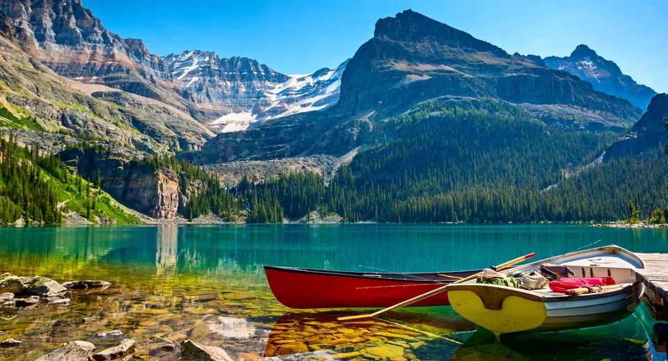 Un tranquillo lago alpino con una barca rossa e gialla davanti a montagne innevate nel campus della St. Margaret’s School.