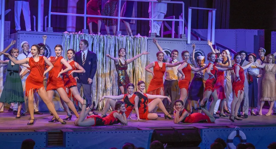 Studenti del Walkerville Collegiate Institute mettono in scena una vivace esibizione di danza con abiti rossi su un palco variopinto.